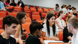 A group of students chatting in a busy lecture theater.