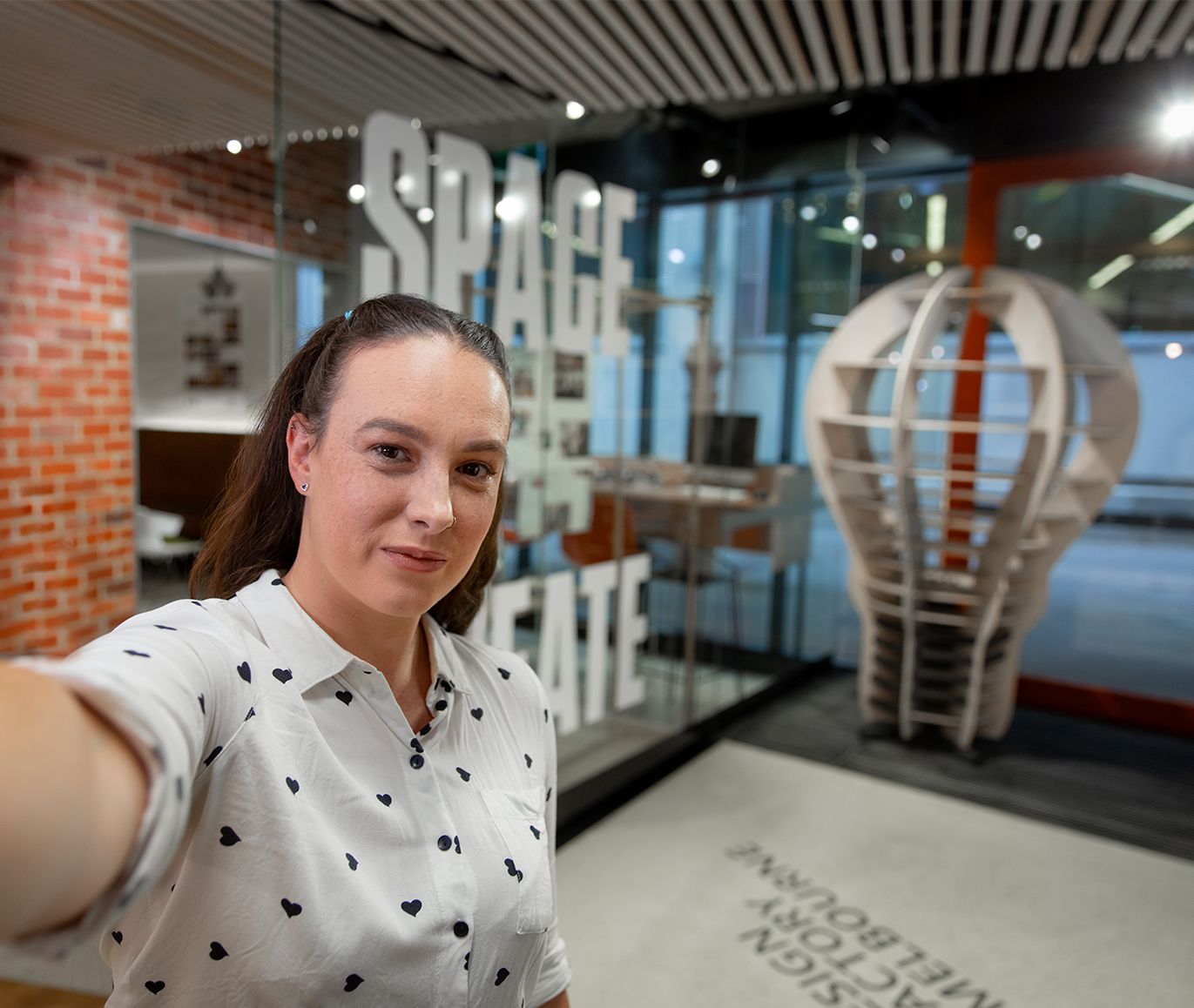Bianca-Jaye taking a selfie in student space on Hawthorn campus Female student takes a photo in a selfie style shot, smiling at the camera with a Swinburne Hawthorn campus space seen in the background.