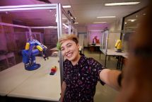 Student seen standing in a Science lab with machinery in background.