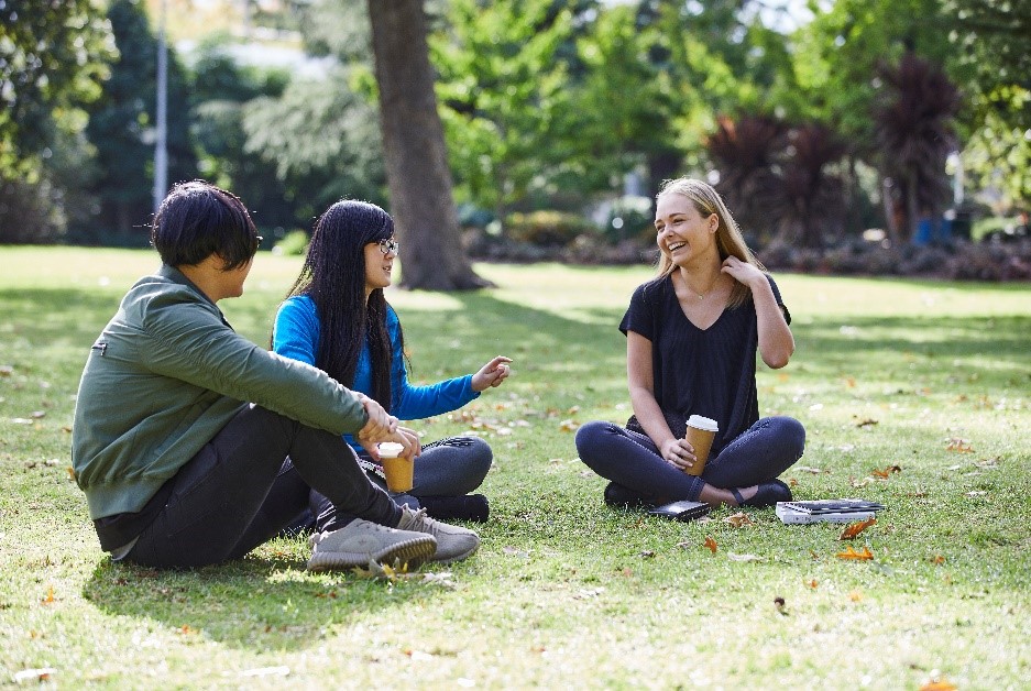caption2-article-jie.jpg Three students sit in the park laughing and drinking coffee