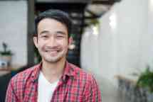 Casually dressed young Asian man smiling towards camera