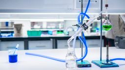 Science lab equipment including a bunsen burner and chemicals in beakers.