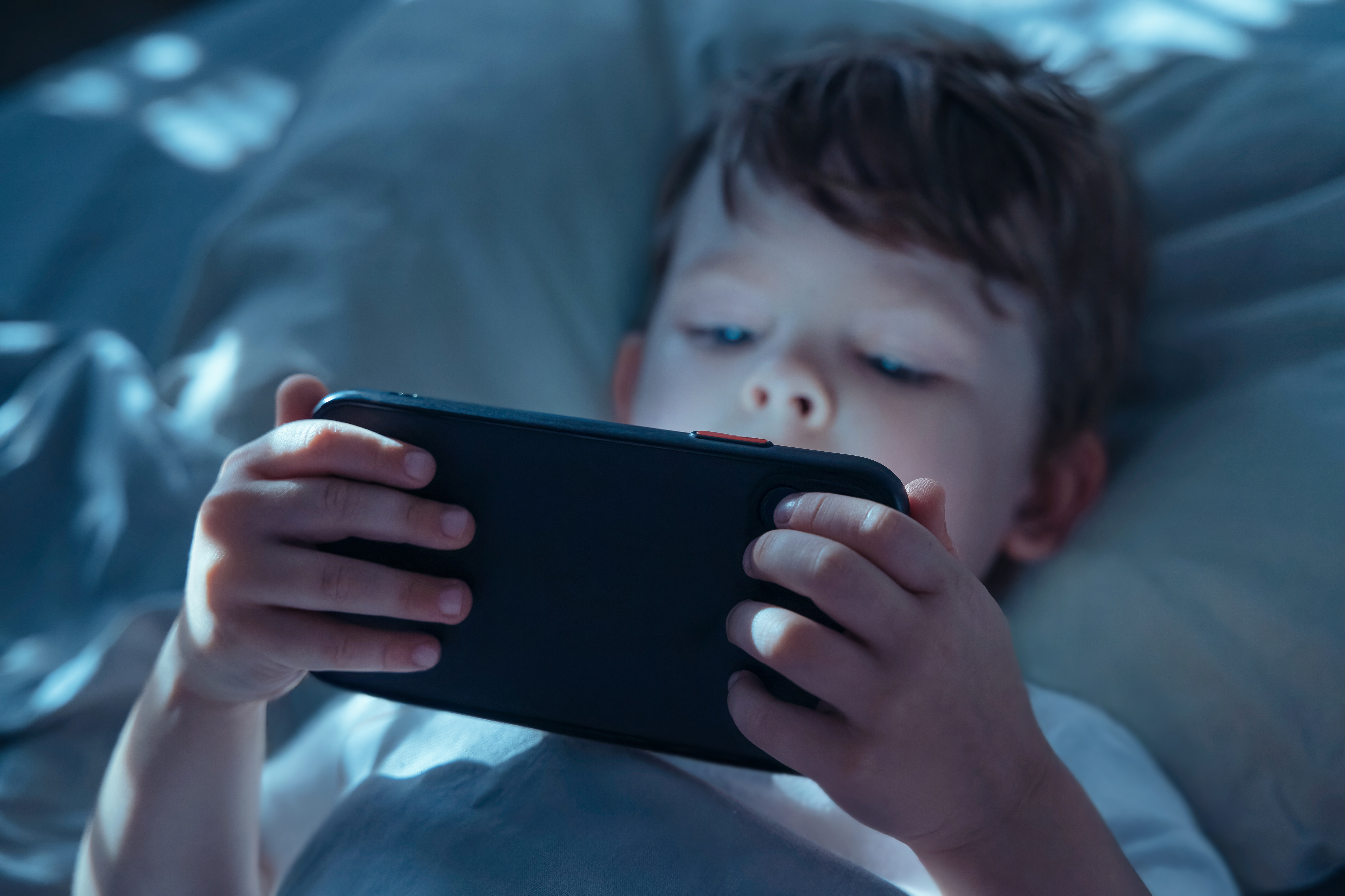 Child Watching Smartphone Screen in Bed at Night