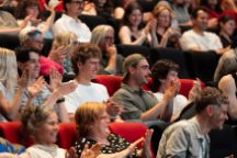 Audience members at Creative Intersections 2024 sitting in a theatre and clapping their hands