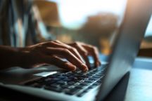 Close up of hands on a laptop keyboard.