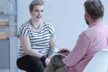 Smiling young woman with tattoos talking with counselor about business