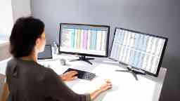 Businesswoman at a workstation analysing computer data across dual monitors.
