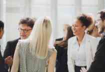 A group of people talking at a networking event. All are smiling and engaged in friendly conversation.