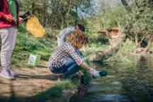 Group of students taking bottles and rubbish out of the river.