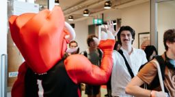 Student in white shirt hi-fiving Swinburne mascot, Razor