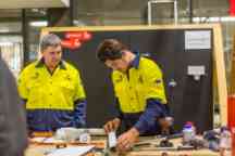 Plumbing apprentice works on a pipe at the Croydon campus as his tutor inspects
