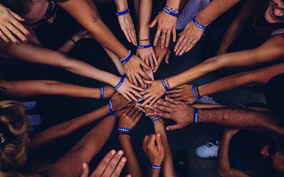A group of people putting their hands in a circle.