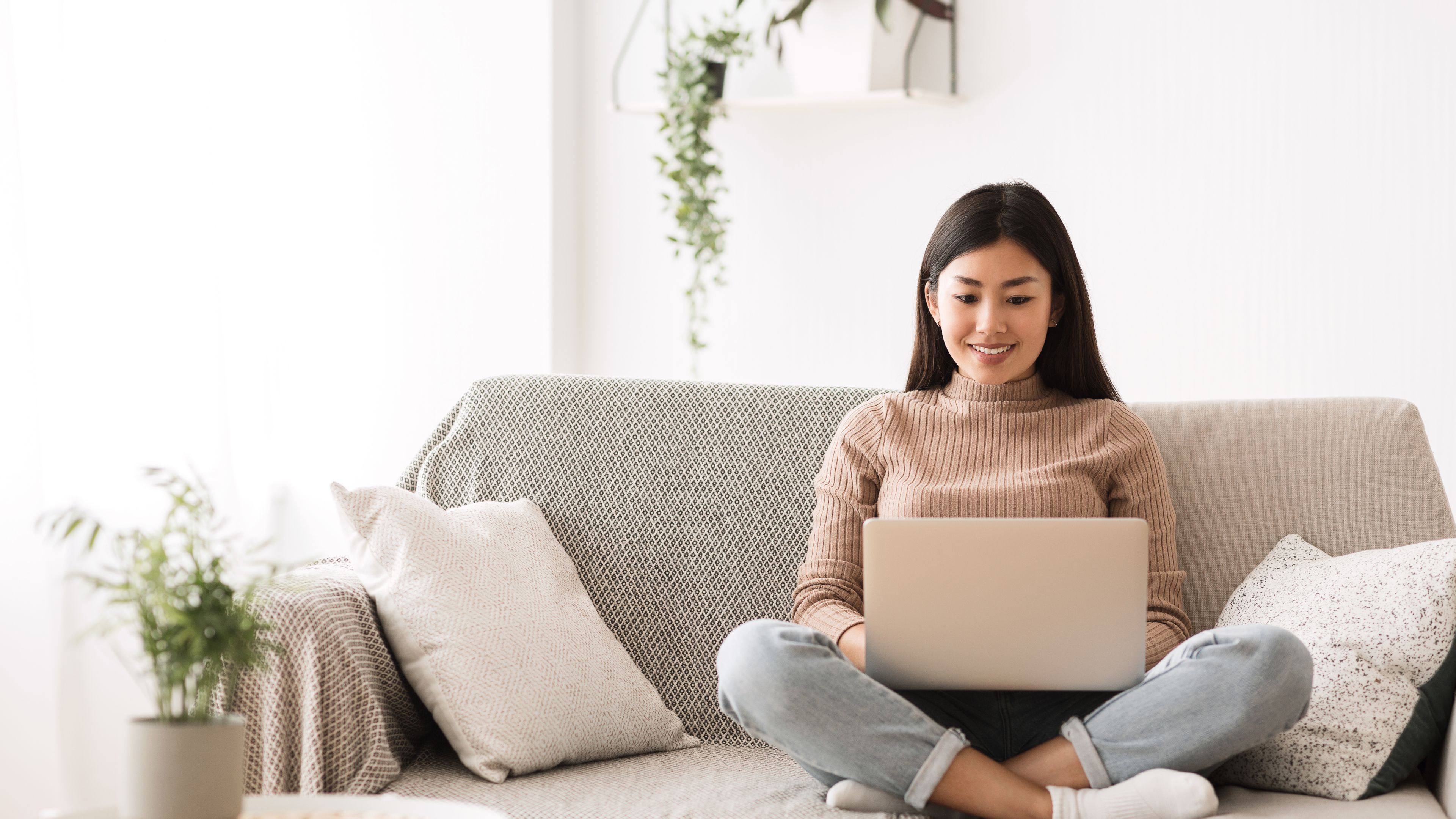 Women sitting on coach with laptop Girl browsing online on paptop