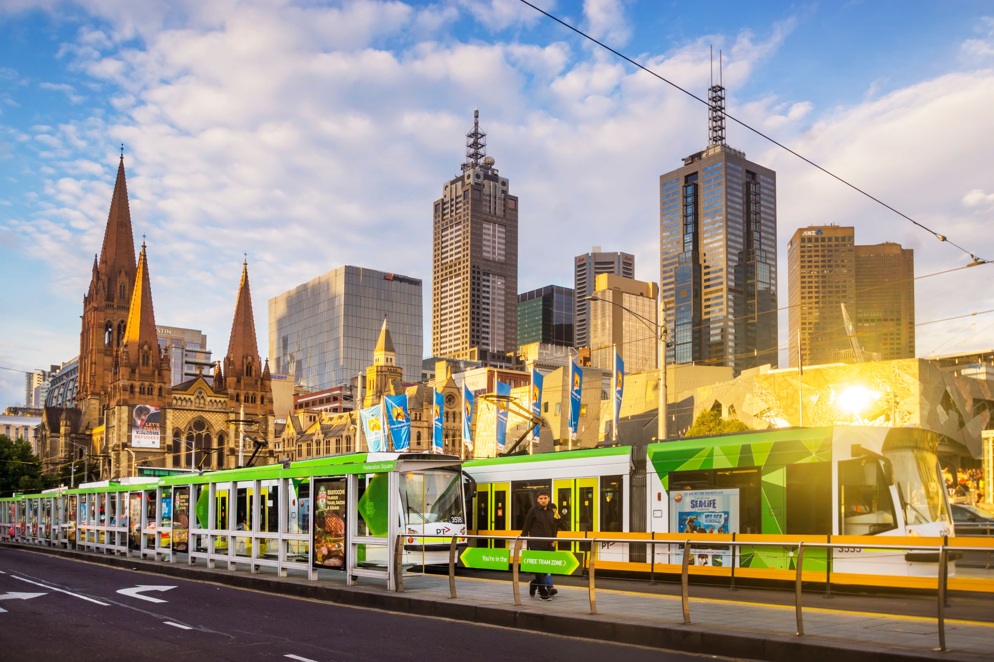 Trams and commuters at a tram stop on St Kilda Road Trams before Melbourne Skyline