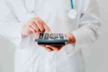 Close-Up of Female Doctor is Calculating Medicine Cost in Office Hospital, Female Medical is Using Calculator. Healthcare and Financial Concept