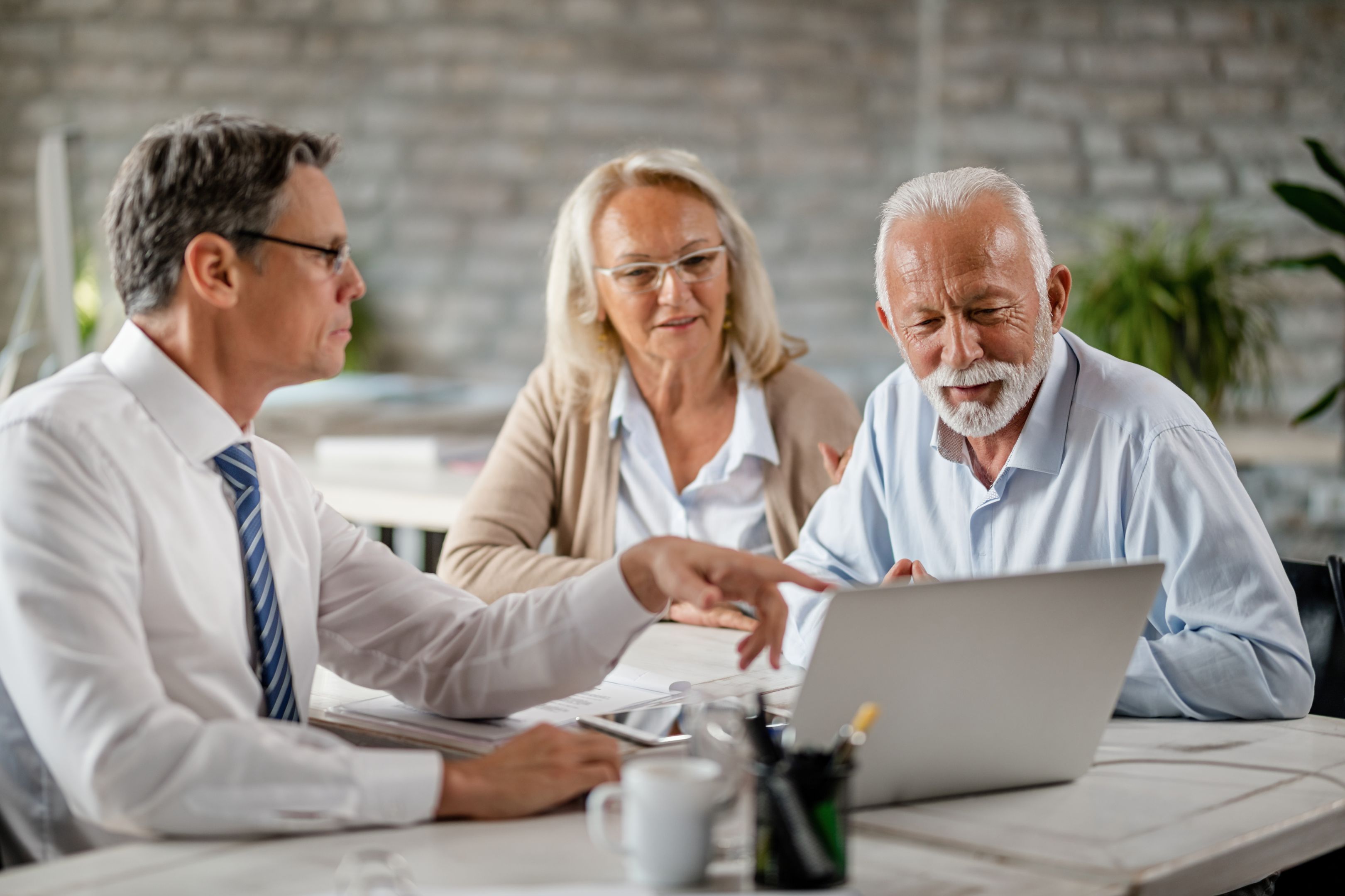 Mature couple and insurance agent using computer during consultations in the office. Mature couple and insurance agent using computer during consultations in the office.