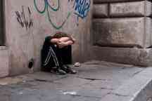Boy huddled and alone on city street