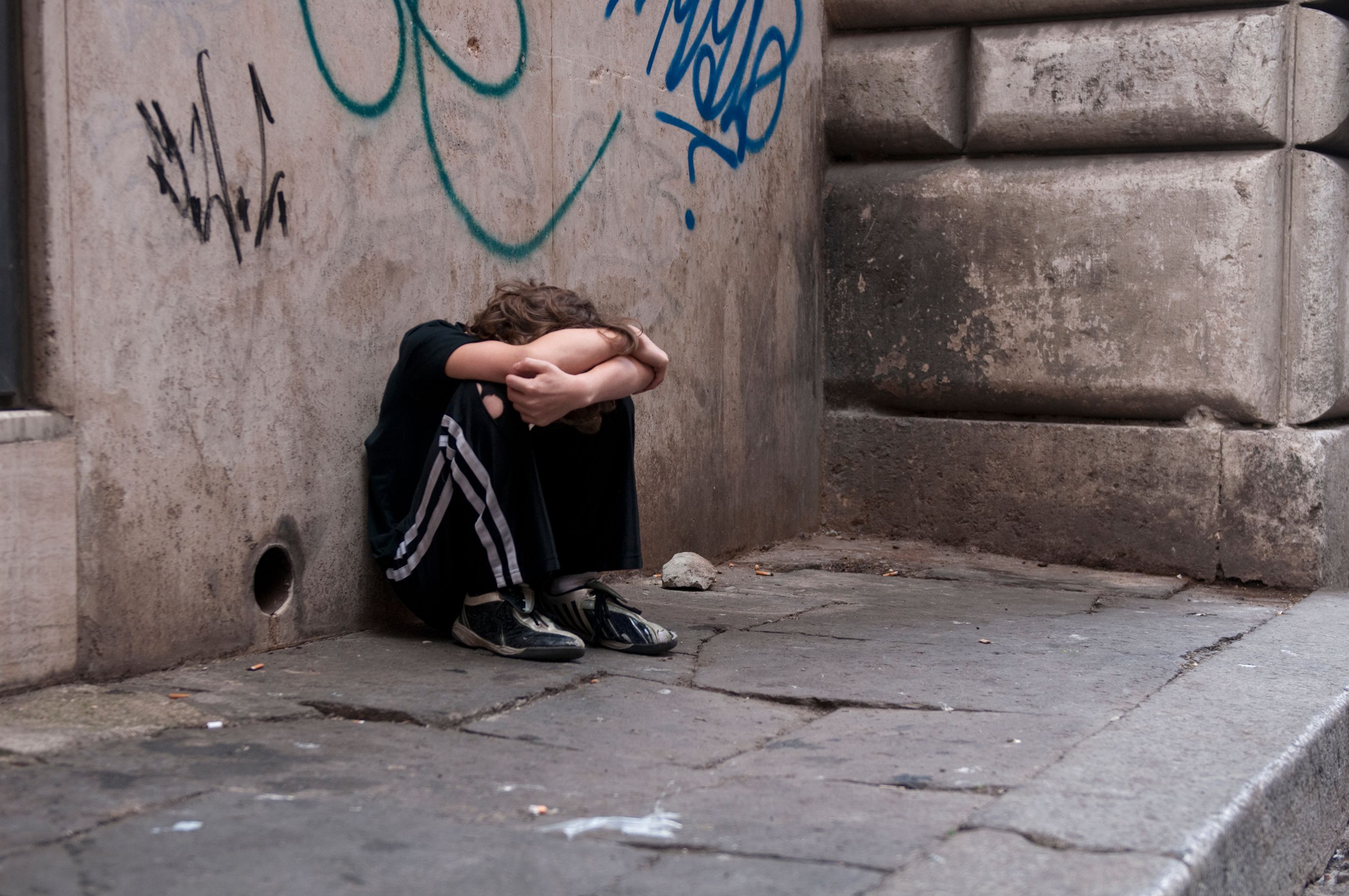 Boy huddled and alone on city street Boy huddled and alone on city street