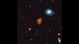 a picture of space, stars and a white glow surrounds a larger red glow in the middle of the picture, this red glow displays the newly discovered galaxy disk the Big Wheel 