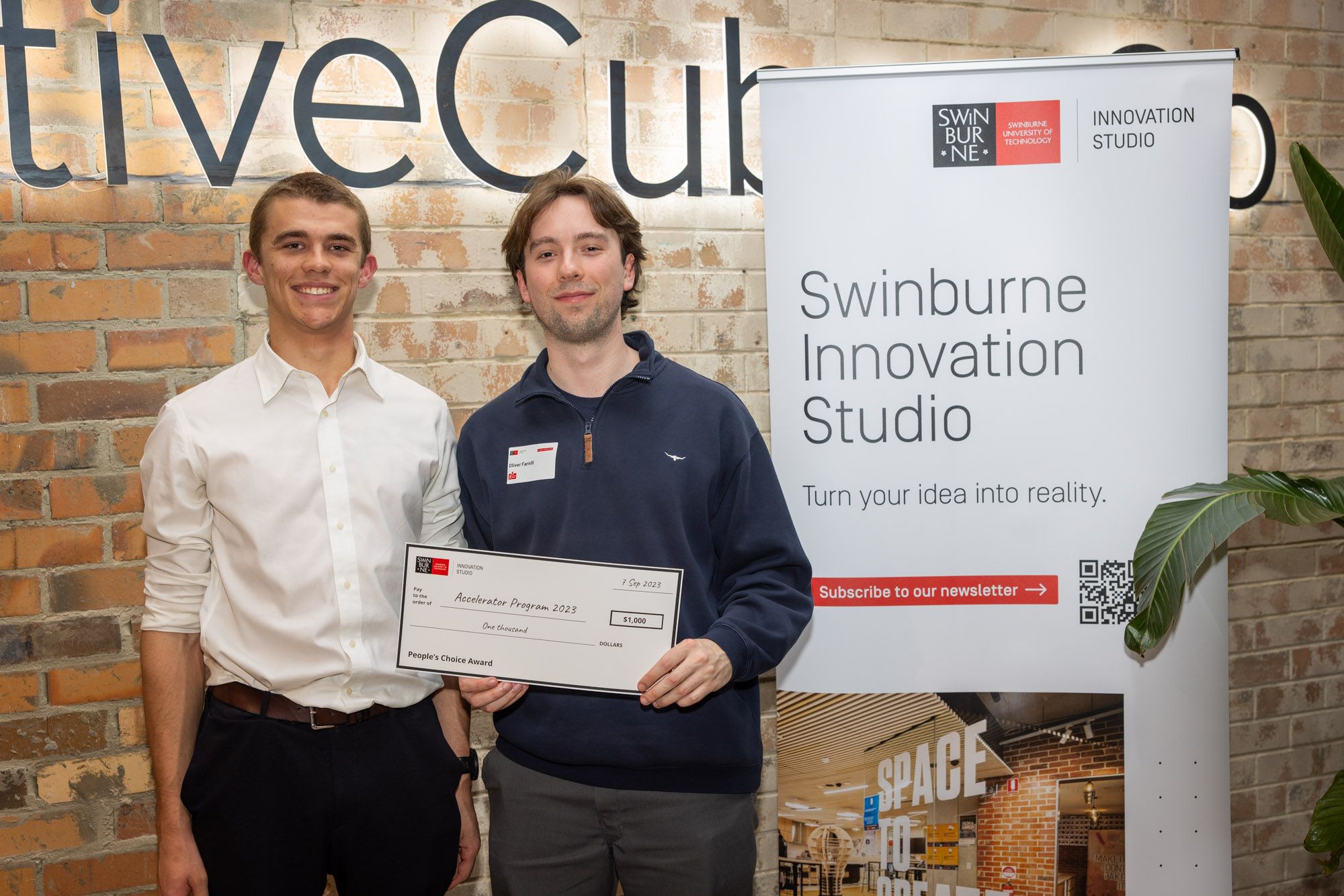 Swinburne Accelerator 2023 Demo Night (Left to right) Finnlay Morcombe and Oliver Farnill stand togetehr smiling holding up the People’s Choice award at the 2023 Swinburne Accelerator Program Demo Night.