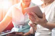 Happy elderly twin senior people society lifestyle with technology concept. Ageing Asia women using tablet  and smartphone share social media together in wellbeing county home.