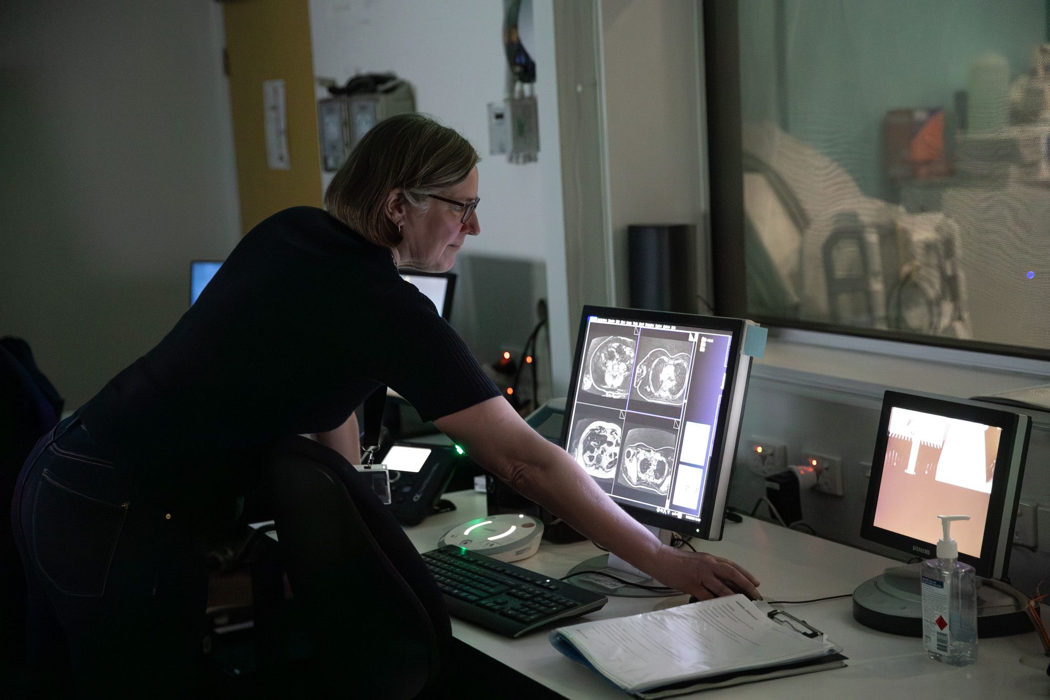 Swinburne radiographer Annalaise Takla looks at MRI data at the Swinburne Neuroimaging facility A woman uses a mouse to scroll through MRI scan data, shown on screen as a cross-section of a human body, inside the Swinburne Neuroimaging facility.