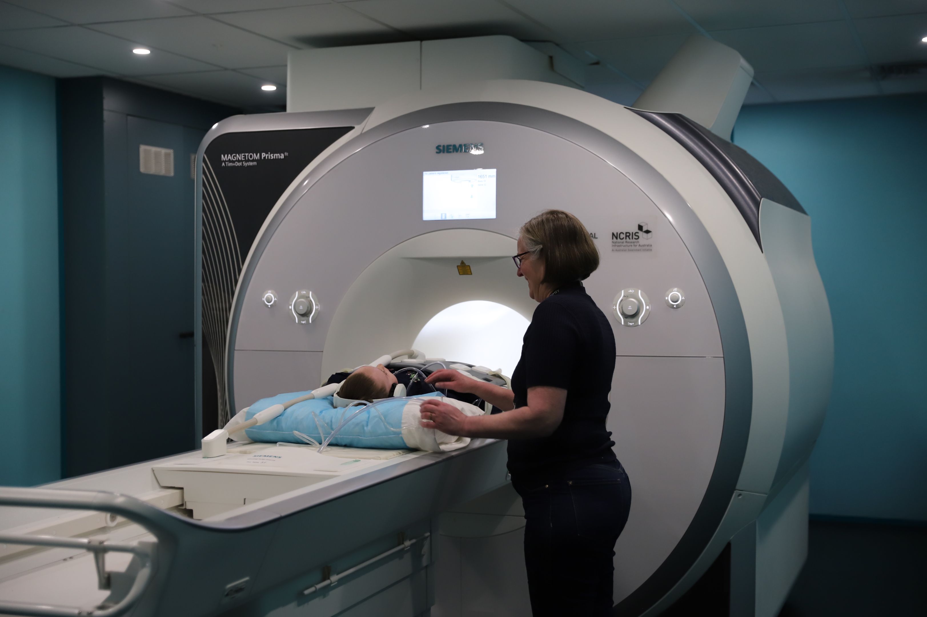 Zaharrah Priestley undergoes an MRI at Swinburne Neuroimaging A young girl lies half-way inside an MRI machine, with a technician standing beside her.