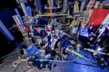 A complex-looking machine with various cables and parts sits in a laboratory. 
