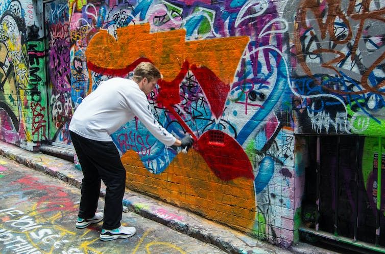 Art Graffiti Man using a spray can to create graffiti art in a Melbourne alleyway