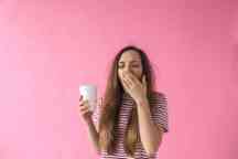 Girl with coffee is yawning.