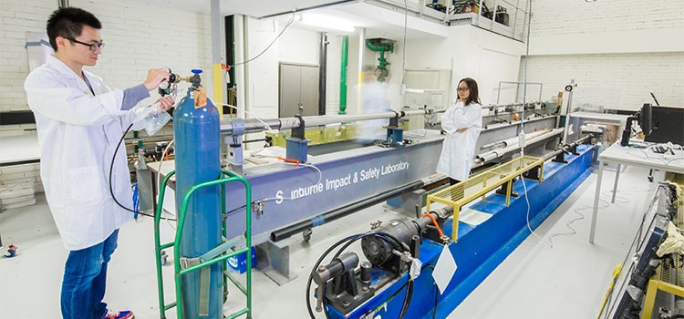 Two engineers using a gas gun inside a laboratory.