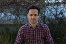Professional headshot of Alex Lloyd, Recruitment Team Leader Marketing and Student Recruitment. Alex is wearing a checkered shirt and the photograph has been taken outdoors.