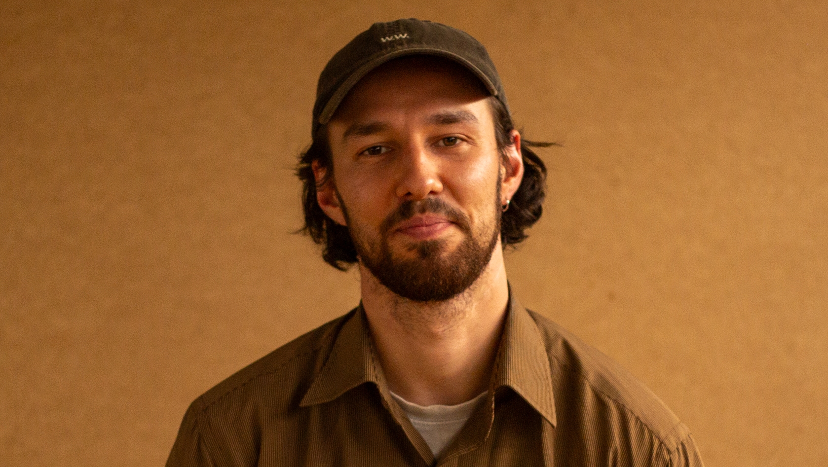 Man sitting down with a brown shirt on