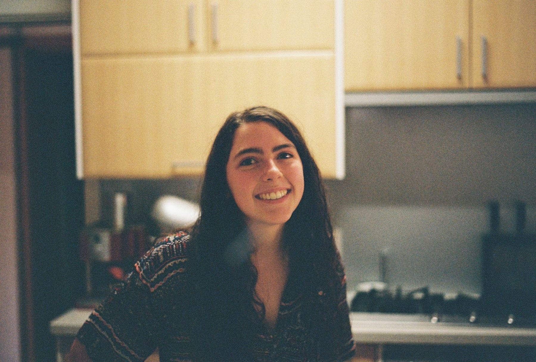 Placement student Claudia A young female student with brown hair, standing and smiling in a kitchen.