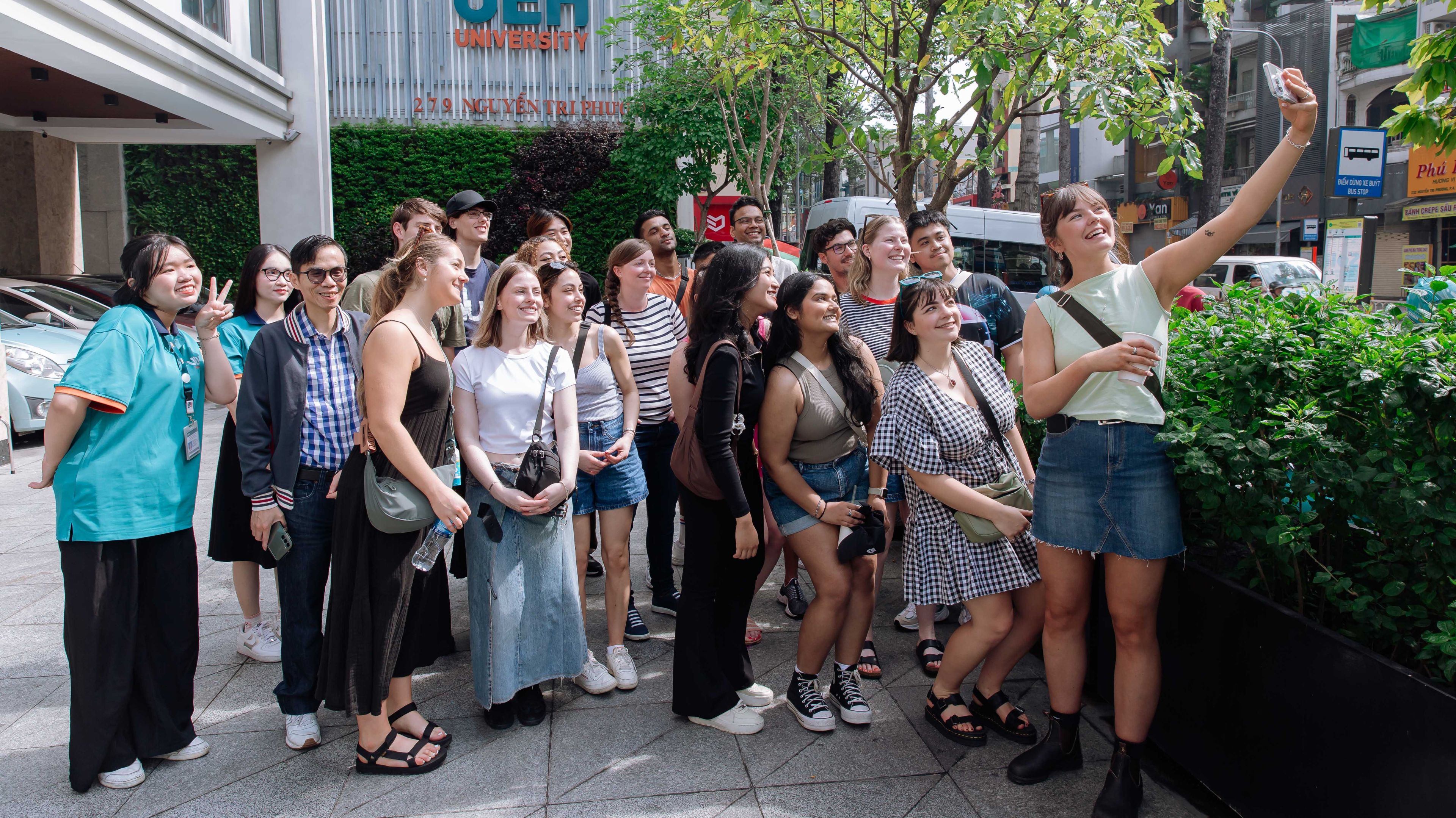 Vietnam Law, Governance and Culture Tour: UEH A large group pf students pose for a selfie outside the UEH campus