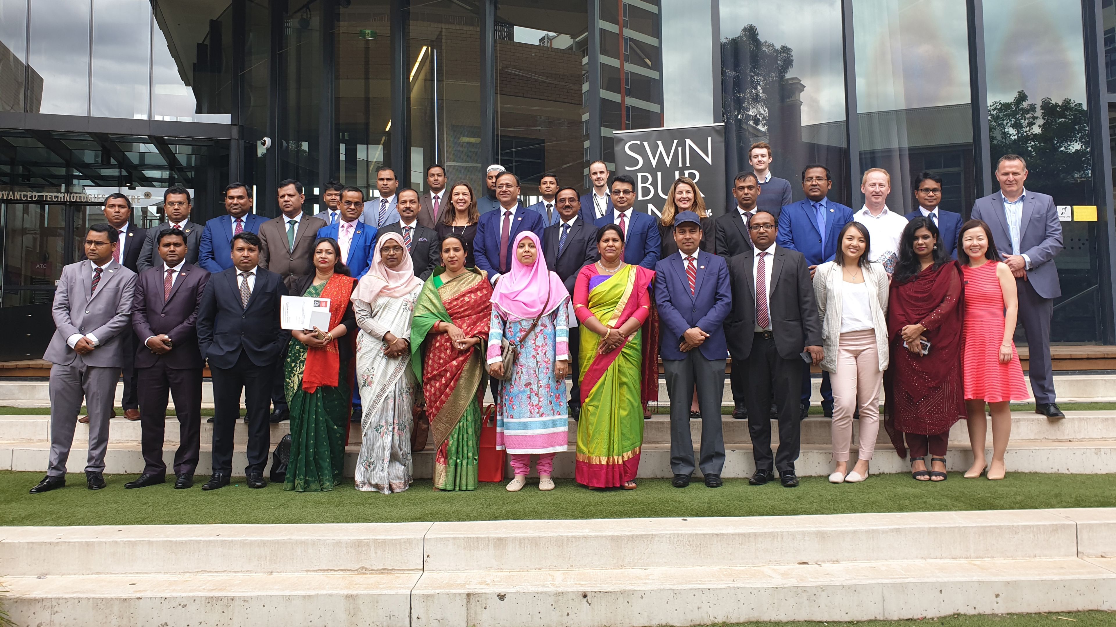 Cabinet of Bangladesh workforce training participants A large group of people standing outside a university building in front of the Swinburne logo.