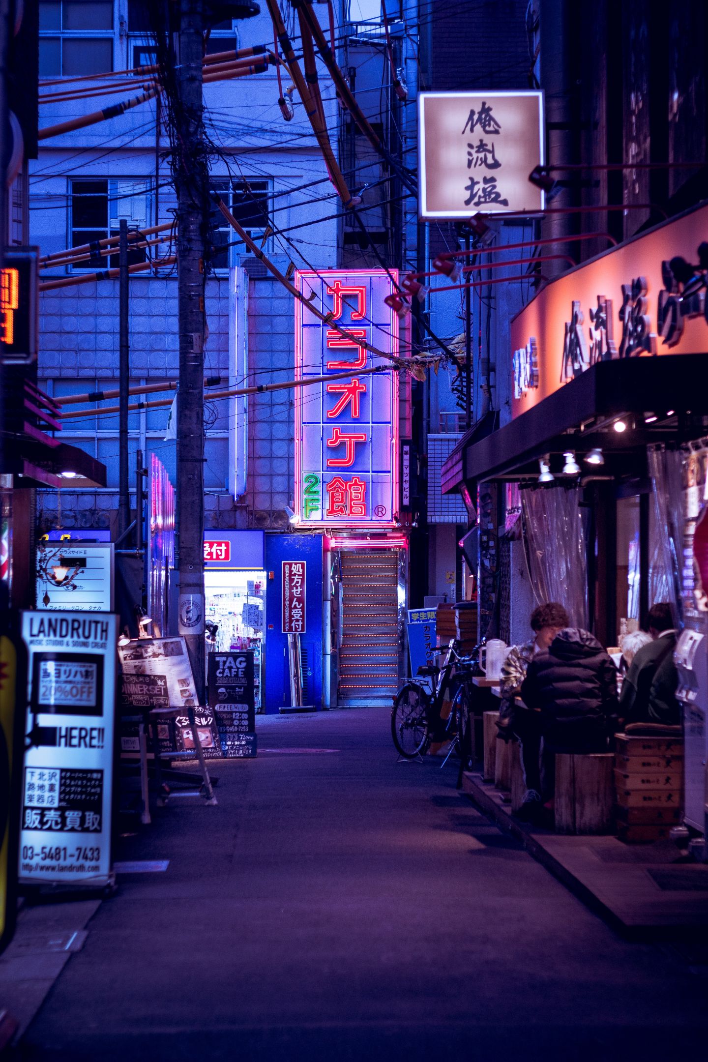 Tokyo by night A night scene of a Tokyo side street featuring neon signs, bicycles and people enjoying food in the street