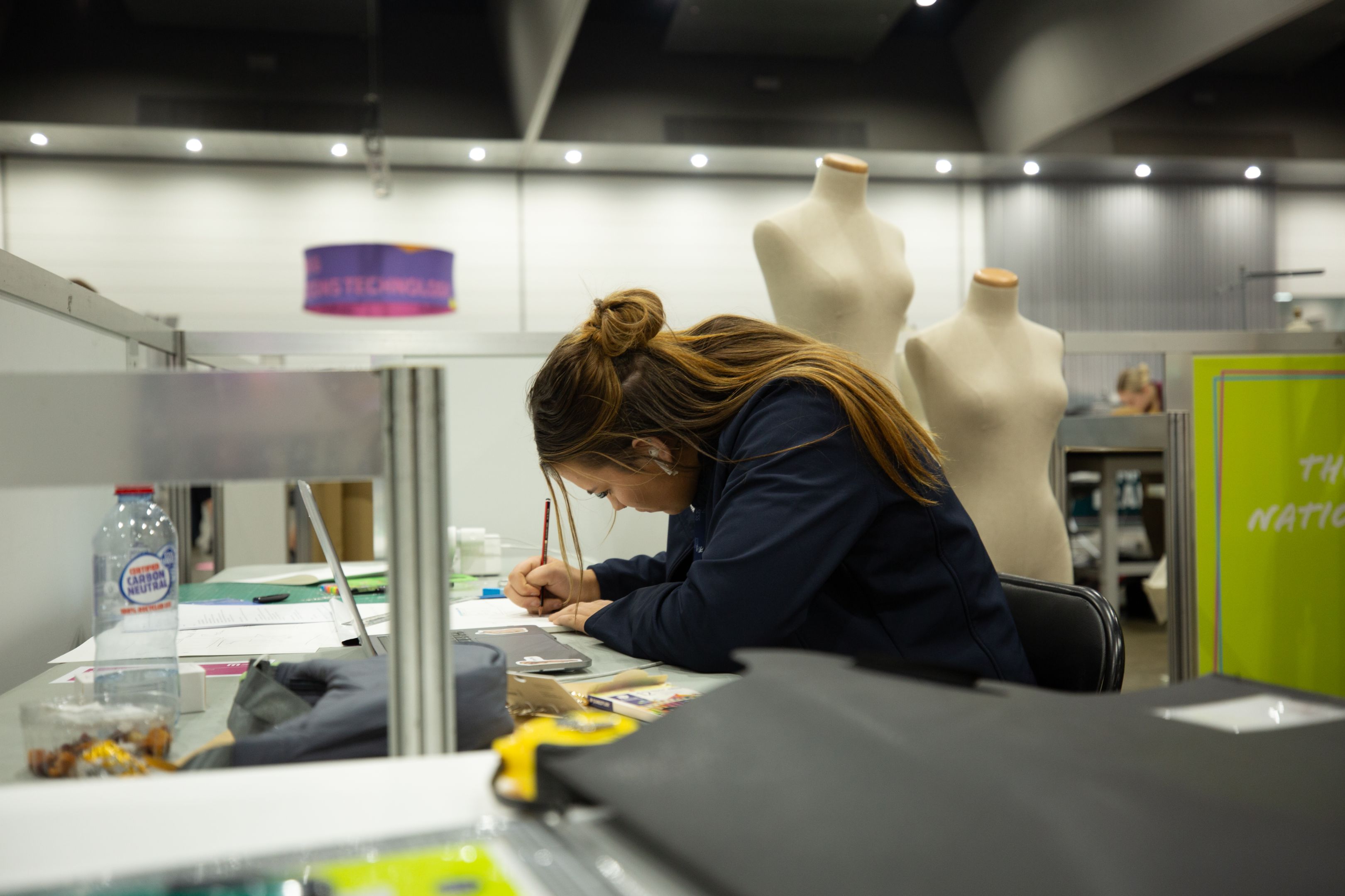 Kaityn Tullber Visual Merchandising Kaitlyn sitting at a desk and drawing up designs