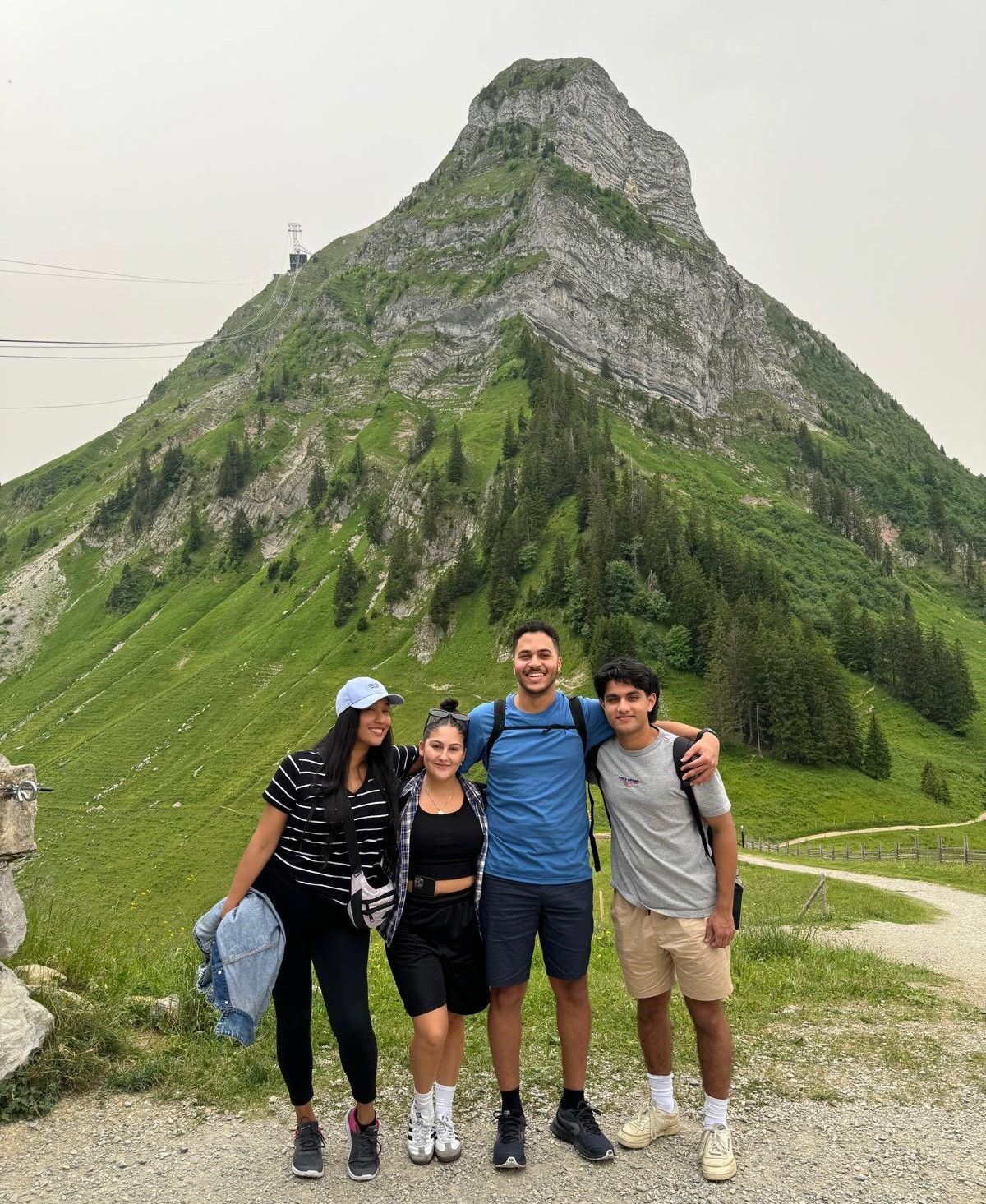 School of Management Fribourg, Switzerland Image of 4 students standing in front of mountain in Switzerland as part of exchange program at School of Management Fribourg.