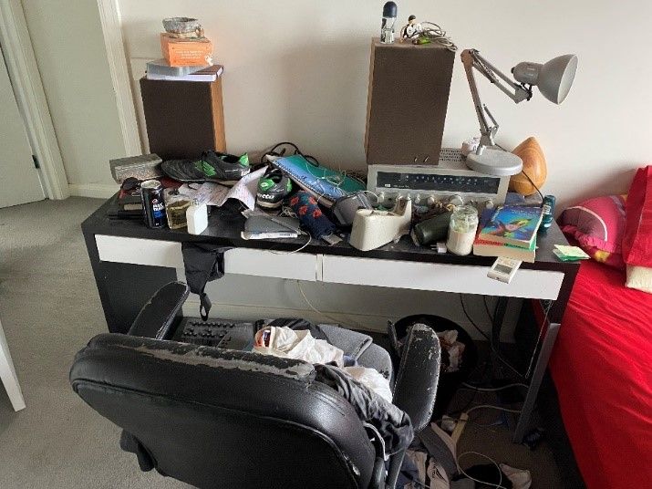 Spencer’s desk (and desk chair) is a dumping ground for everything besides his uni work. Spencer’s desk, littered with miscellaneous personal items such as shoes, socks, deodorant cans and a defunct antique radio.
