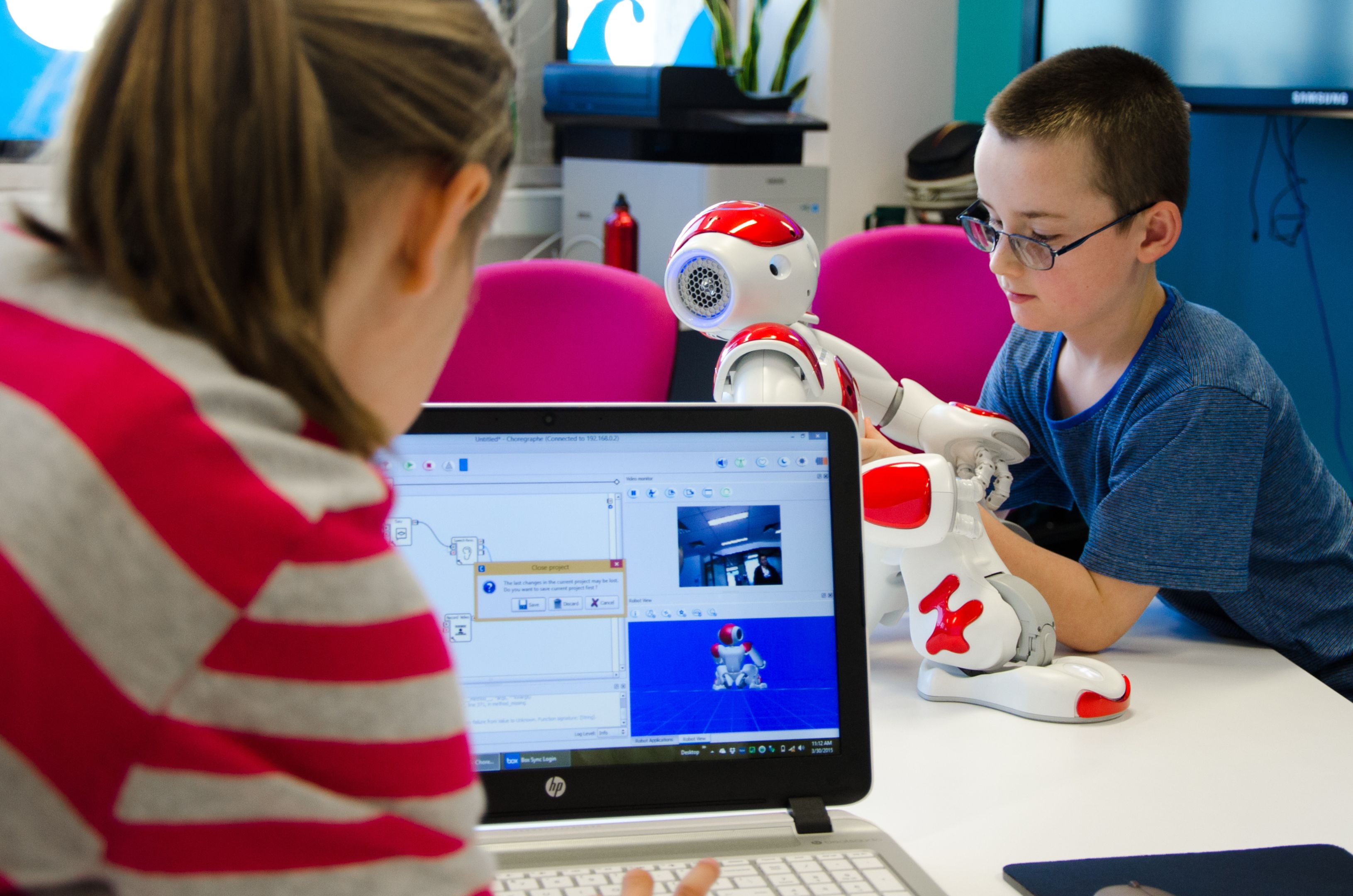 Child with robot Woman looks at laptop while child plays with robot