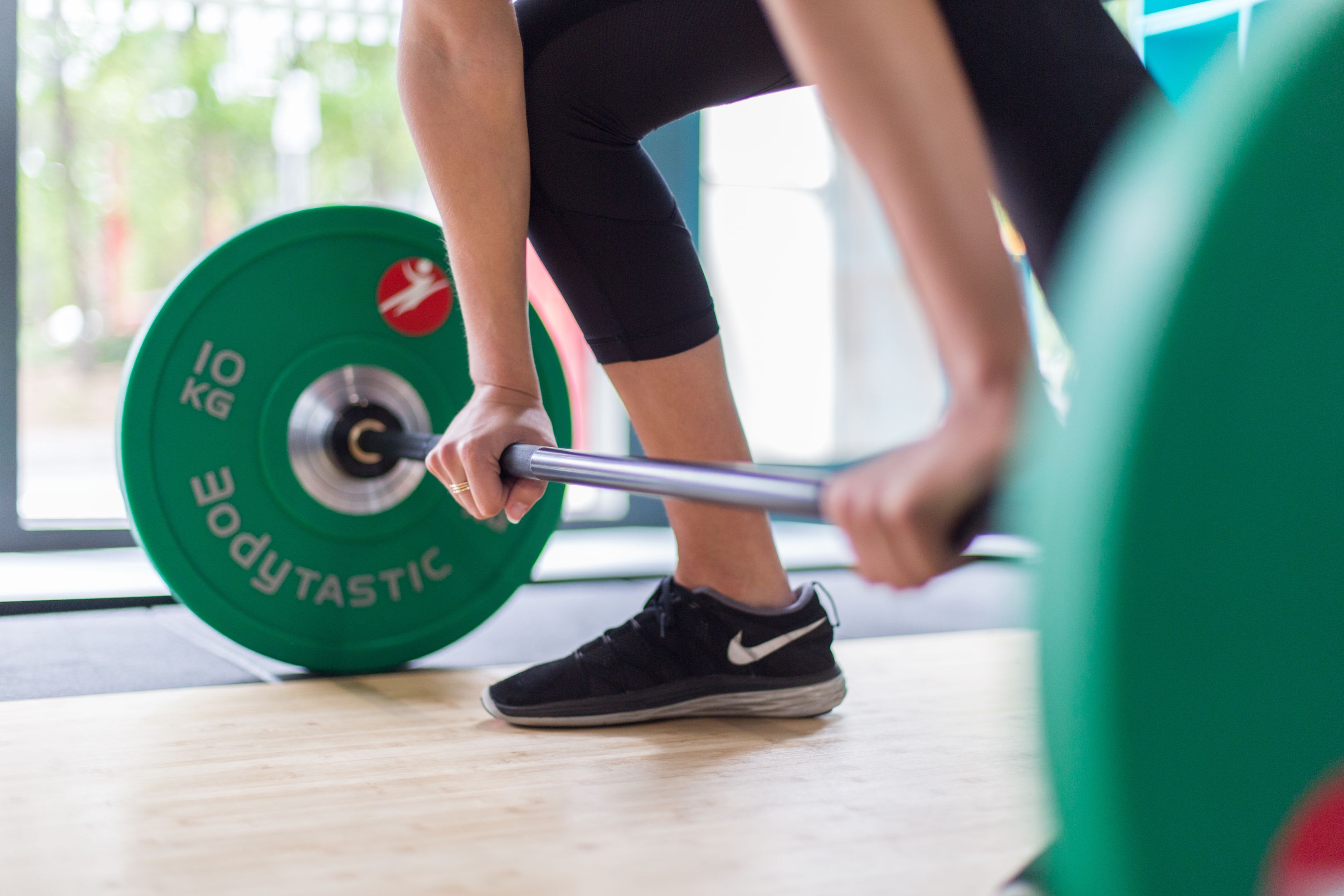 Student using weight training equipment as part of their exercise sport science studies. Student exercises in the gym about to lift green weights